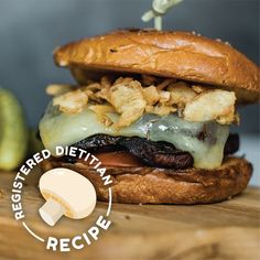 a cheeseburger on a wooden cutting board with an apple in the back ground