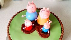 three peppa pig cakes on top of a green plate with chocolate frosting and decorations