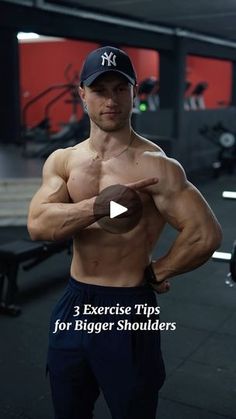 a man with no shirt in a gym holding his hands out to the side and pointing at