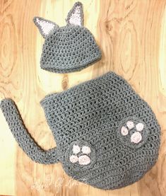 a crocheted cat hat and diaper cover on a wooden surface with the top half off