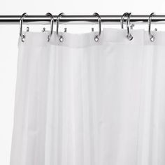 a white shower curtain hanging on a metal rod