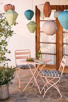 two chairs and a table outside with paper lanterns hanging from the ceiling