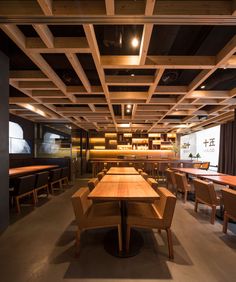 an empty restaurant with wooden tables and benches in the foreground is lit by spotlights