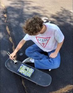 a young man sitting on the ground with his skateboard in front of him,