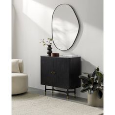 a black cabinet with a round mirror above it and potted plants next to it