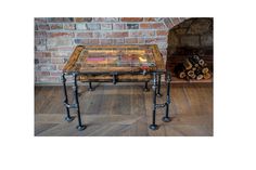 a coffee table made out of wood and metal pipe legs with a glass top sitting in front of a brick wall