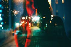 a blurry image of a woman standing in front of a car with her hand on her face