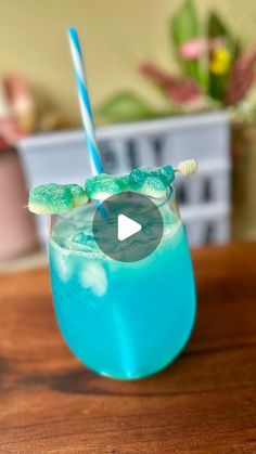 a blue and green drink sitting on top of a wooden table with a straw in it