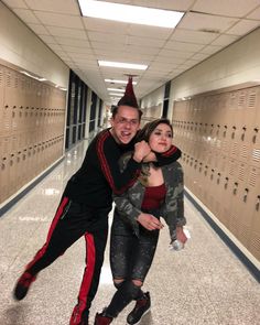 a man and woman are posing for a photo in a hallway lined with lockers