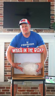 a man sitting in front of a fireplace holding a box with a turkey inside it