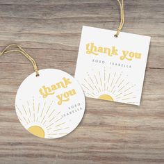 two tags with thank you written on them sitting next to each other in front of a wooden table