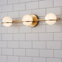 three lights mounted on the side of a brick wall next to a white tiled wall