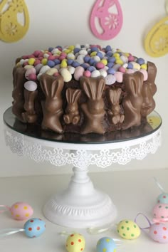 there is a cake on the table with chocolate bunny decorations and candy eggs around it