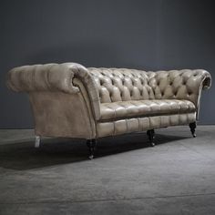 an old leather couch sitting on top of a cement floor next to a gray wall