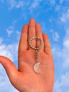 a hand holding a keychain with a clear piece of glass hanging from it