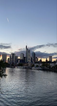 a city skyline is seen from across the water at sunset or dawn with clouds in the sky