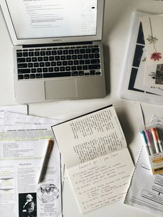 a laptop computer sitting on top of a white desk next to papers and pencils