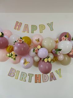 a bunch of balloons that are sitting on a wall with the words happy birthday written in gold