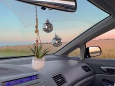 an air plant hanging from the dashboard of a car with disco balls attached to it