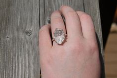 a person's hand with a ring on it that has a large diamond in the middle