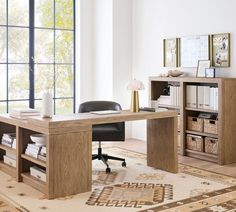 a wooden desk sitting in front of a window next to a book shelf filled with books