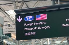 an airport sign with foreign and american flags on it