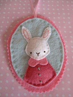 a felt bunny ornament hanging on a pink polka dot background