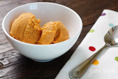 two scoops of pumpkin ice cream in a white bowl on a polka dot napkin