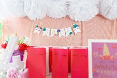 a birthday party with pink and white decorations on the wall, paper bags and greeting cards