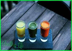 three different colored drinks sitting on top of a wooden table