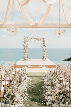 an outdoor ceremony setup with white flowers and greenery on the aisle, overlooking the ocean