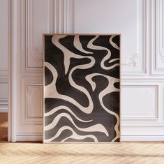 an abstract black and white painting in a frame on the floor next to a wall