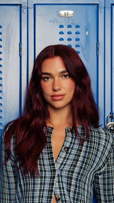 a woman with red hair standing in front of blue lockers and posing for the camera