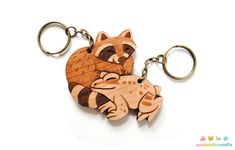 a wooden key chain with a raccoon on it's back and an animal in the middle