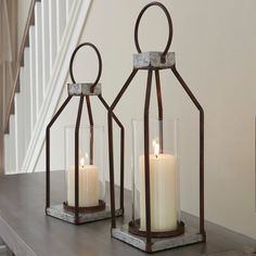 two candles are sitting on a shelf next to some glass vases with one candle in it