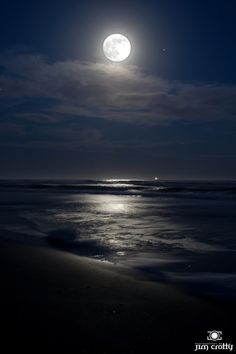 the moon is shining over the ocean at night