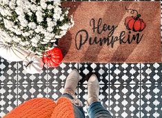 a person standing in front of a door mat with the words hey pumpkin on it