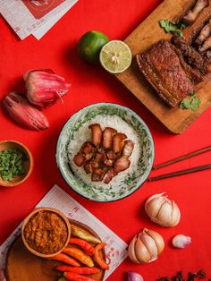 some food is on a red table with chopsticks and other foods around it