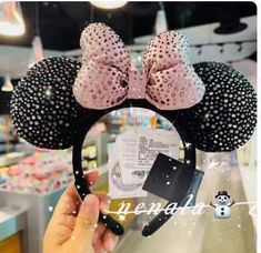 a person holding up a minnie mouse ears headband in front of a store display