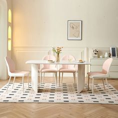 a white table with four pink chairs around it in front of a wall and window