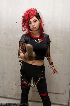 a woman with red hair wearing black clothing and holding a brown object in her hand