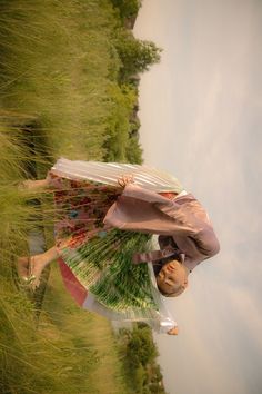 a woman is holding an umbrella while standing in the middle of some tall green grass