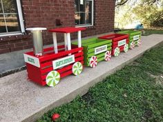 a red and green train sitting on top of a cement slab next to a brick building