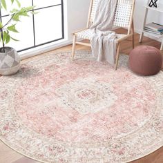 a round rug with an ornate design in pink and beige colors on a wooden floor