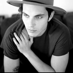 a young man wearing a fedora sitting on a couch