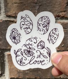 a hand holding up a sticker with flowers on it