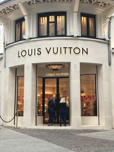 two people standing in front of a louis vutton store