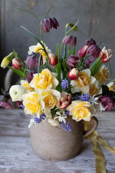 a vase filled with lots of flowers sitting on top of a wooden table next to a yellow ribbon