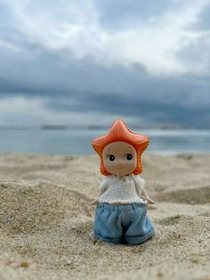 a small doll sitting on top of a sandy beach