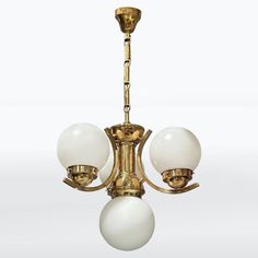 an antique brass chandelier with three white glass balls